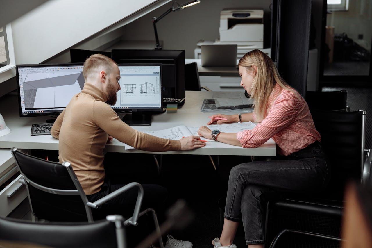 our-story Two architects discuss plans in a contemporary office, focusing on project details.